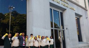 Trabalhadores da limpeza erguem as mãos vestidas com luvas amarelas na Avenida Paulista